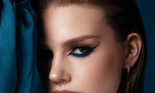 Beautiful woman with blue fabric and classic arrows art make-up. Beauty face. Photo taken in the studio