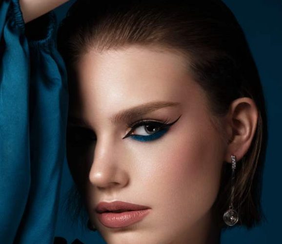 Beautiful woman with blue fabric and classic arrows art make-up. Beauty face. Photo taken in the studio